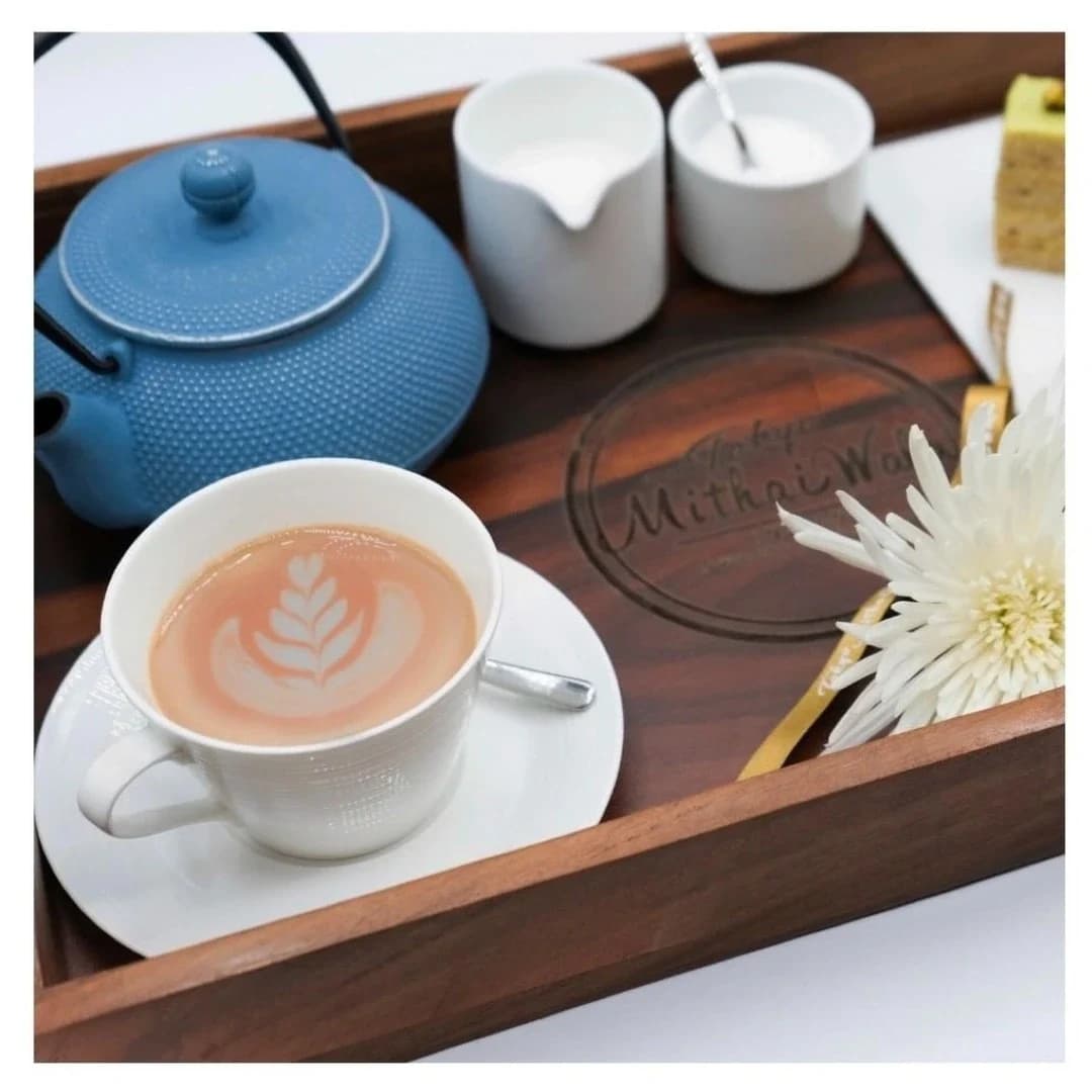 Latte art in a teacup on a wooden Tokyo Mithaiwala tray